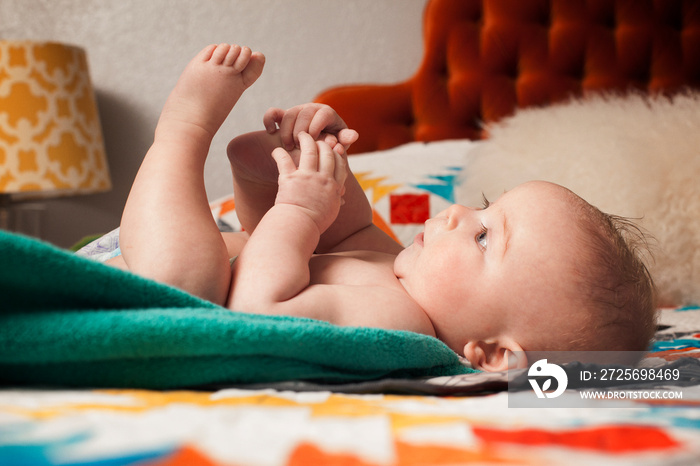 Little boy (2-5 months) lying on bed