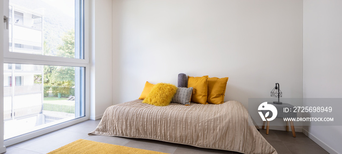 Nice bedroom with a bed, sidetable and lots of pillows. Detail of the bed with a large white wall, p