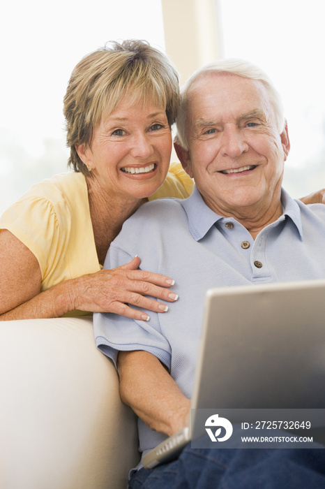 Couple in living room with laptop smiling