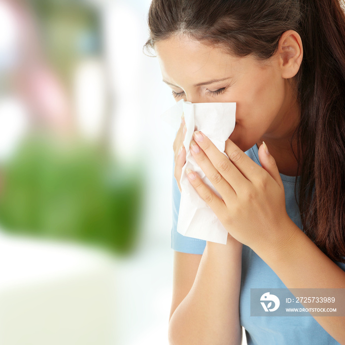 Spring allergy symptoms concept. Teen woman with pollen allergic symptoms blowing nose.