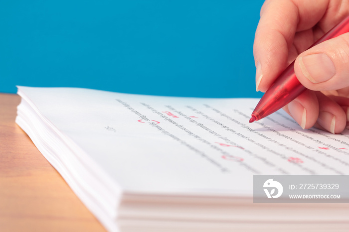 Hand with Red Pen Proofreading a Manuscript Closeup