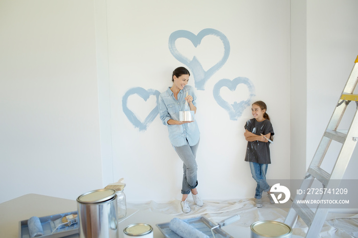 母亲和女儿在墙上画蓝色的心