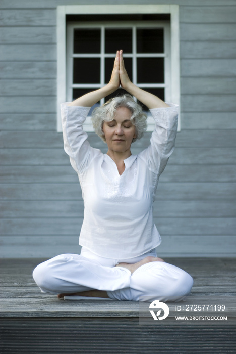 Seniorin macht Yoga auf Sonnenterrasse