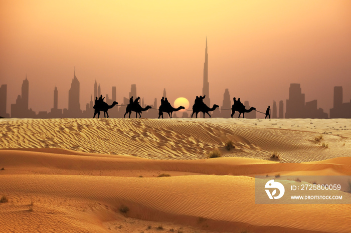 Man and camels in caravan with tourists on sand dunes of Arabian dessert, Dubai skyline seen away 