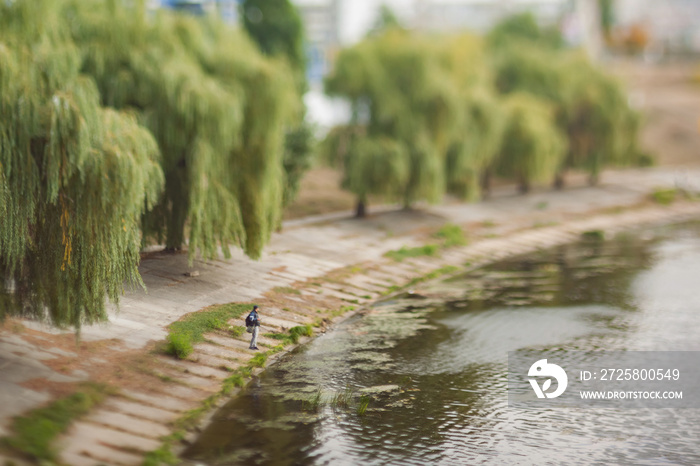 The man is fishing on the canal. Soft and blurry cityscape. Natural optical tilt shift photo.