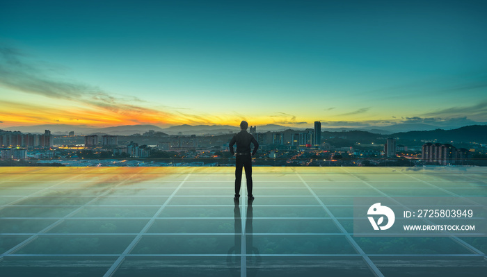 Businessman standing at transparent glass floor on rooftop with city skyline, success and thinking c