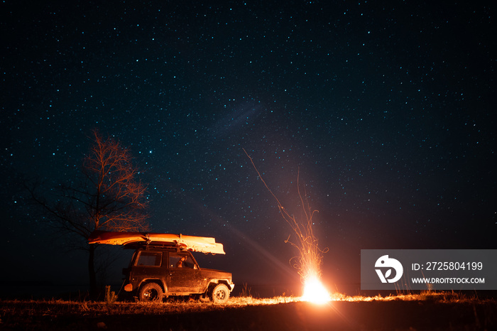 Night landscape with bright campfire and car