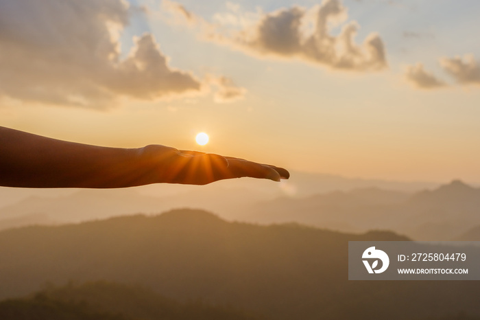 Silhouette female hands holding sun on mountain