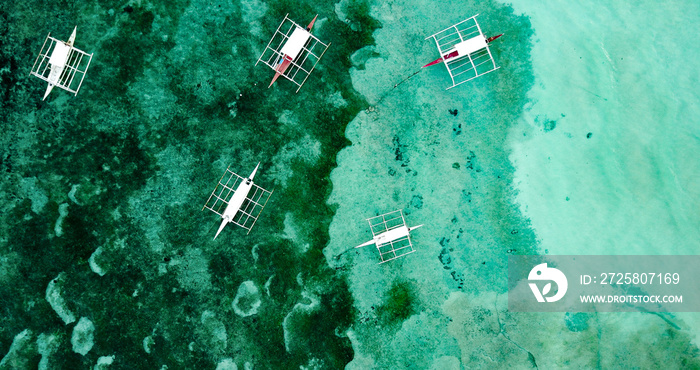 Aerial view of few fishing boats floating on the water in Bohol island, Philippines. Crystal clear w