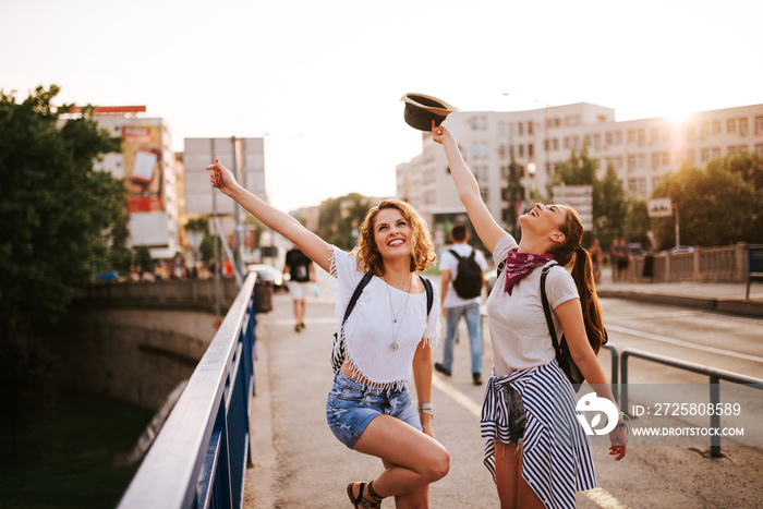 Summer vacation, holidays, party, festival and people concept. Two girls dancing on the city bridge.