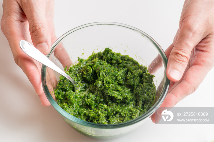 pesto sauce in a bowl on a white background. Hands holding a bowl with pesto