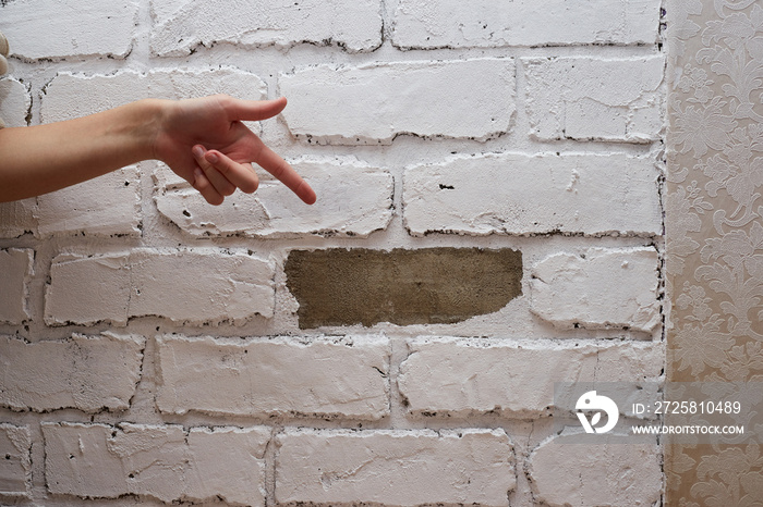 The girl points her finger at a fallen tile of decorative plaster