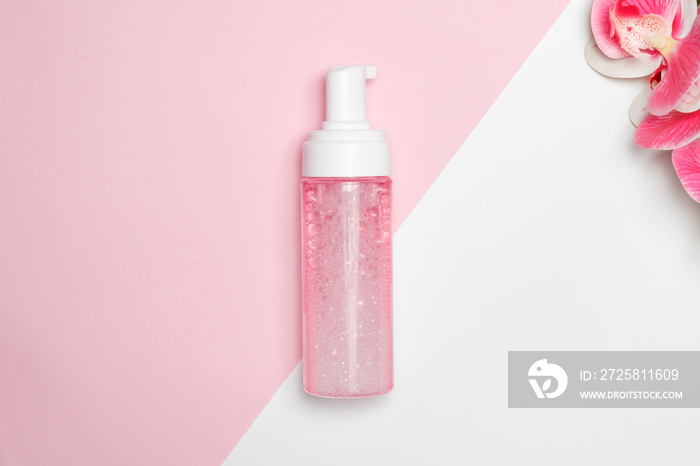 Facial foam in a plastic bottle with an orchid on the background.