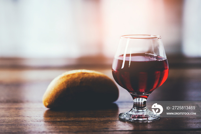 基督，圣餐用木桌上的面包和一杯带荆棘冠的葡萄汁特写