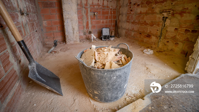 Bucket full of rubble, shovel and empty room