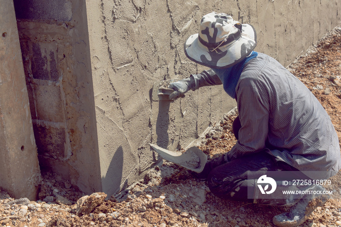 Construction workers plastering building wall using cement plaster