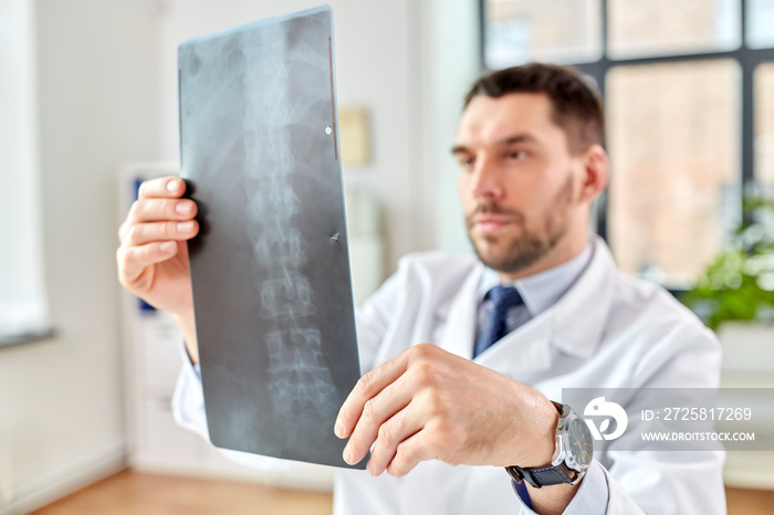 healthcare, medicine and people concept - male doctor with x-ray of spine at hospital