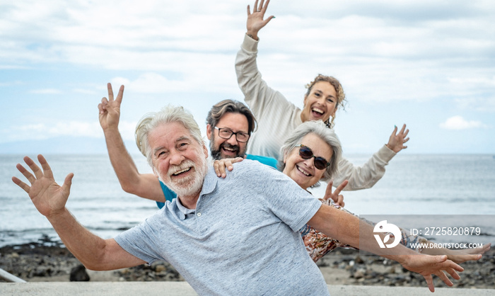 Group of happy people having fun together at sea, cloudy sky. Multi generation family gesturing posi