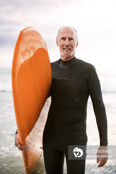 Portrait of senior surfer standing on beach