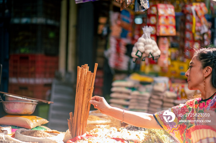 Mujer indígena en un mercado de Quetzaltenango toma con su mano una barrita de canela. 