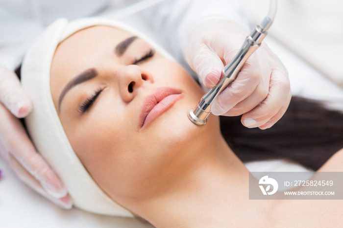 portrait of a woman receiving diamond microdermabrasion treatment. skin care, beauty salon, close up