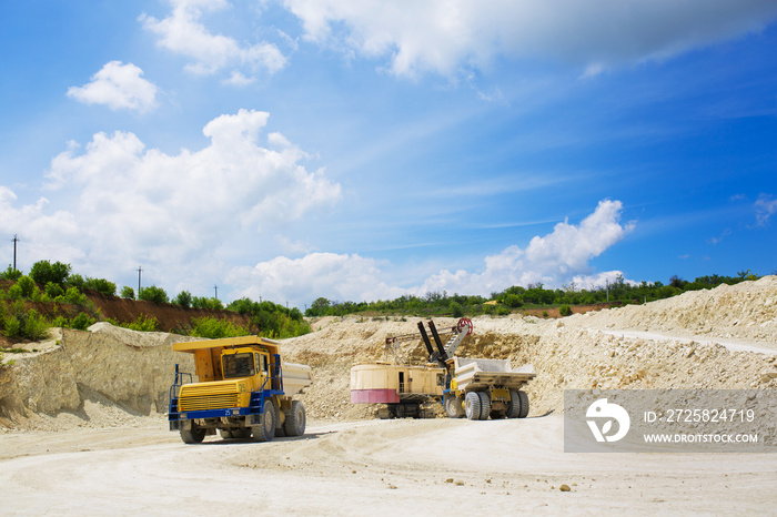 An excavator loads a huge truck with rock.