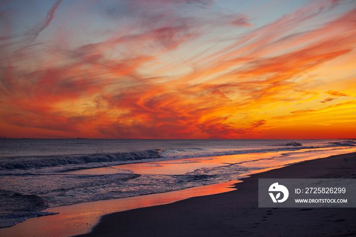 Vibrant pink and orange sunset over small waves breaking on the beach. Jones Beach, Long Island New 