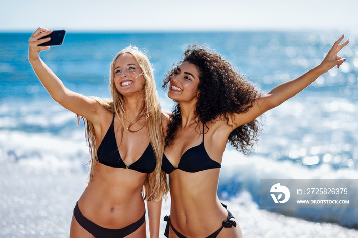 两名女子在海滩上用智能手机自拍