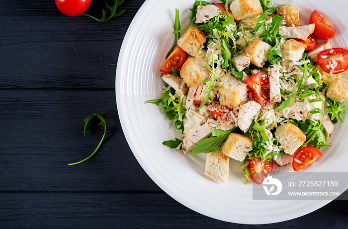 Healthy grilled chicken Caesar salad with tomatoes, cheese and croutons. North American cuisine. Top