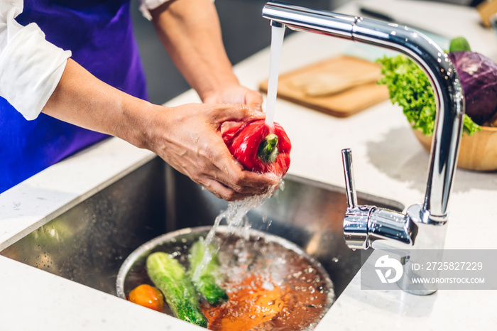 Portrait of man chef cooking and preparing wash fresh vegetables salad splashing in water with cook 