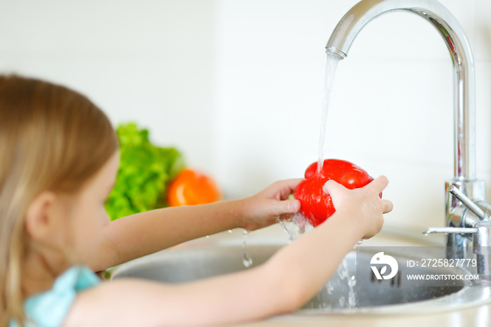 Adorable girl washing vegetables in a kitchen