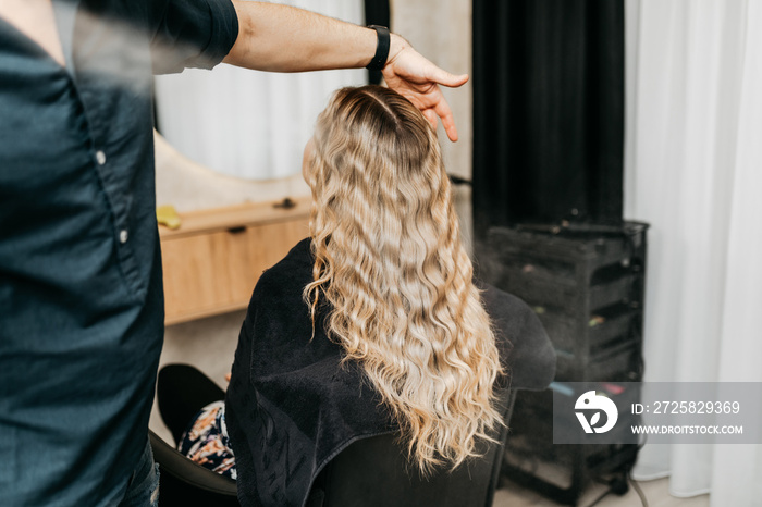 Beautiful blonde wavy hair of a young woman after a treatment in a hair salon.