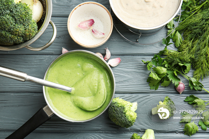 Saucepan with delicious broccoli cream soup on wooden table