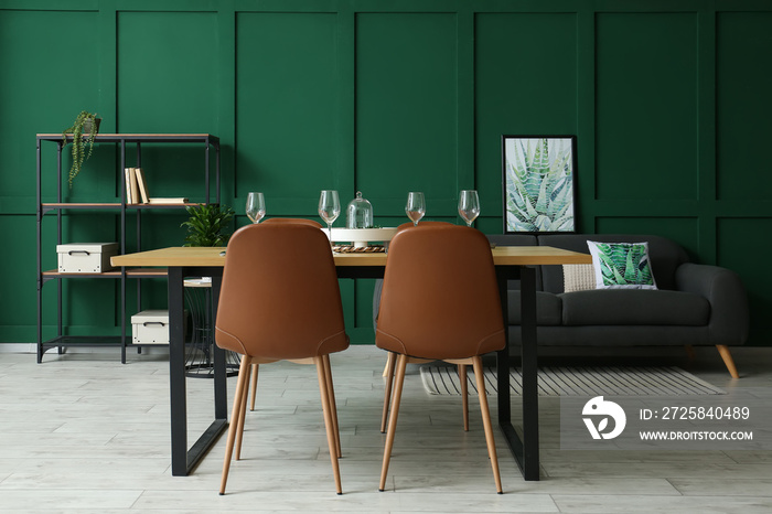 Interior of stylish dining room with table, shelving unit and sofa