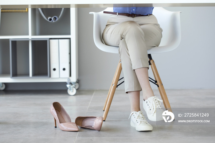 Young woman suffering from foot pain in office