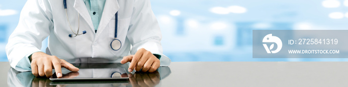 Male doctor sitting at table with tablet computer in hospital office. Medical healthcare staff and d