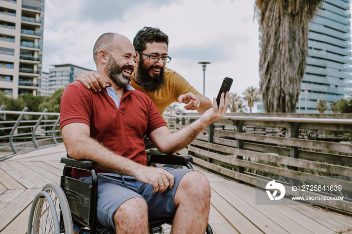 a disabled man on wheelchair with his assistant looking to a mobile phone