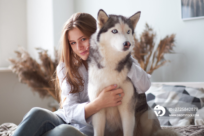 blonde girl playing with her dog husky at home.