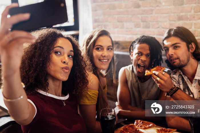 Diverse group of friends enjoying meal and taking selfie