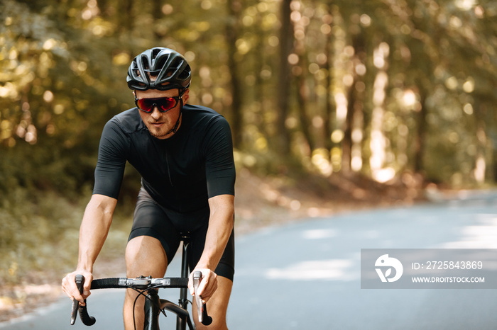 Bearded man with athletic body wearing sport clothing, protective helmet and sunglasses riding black