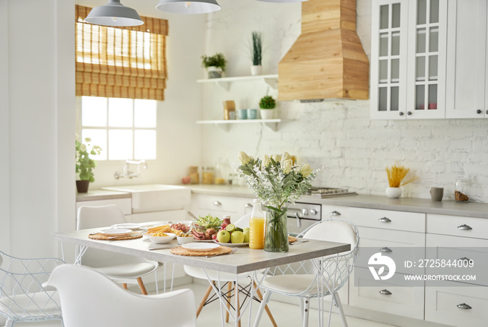 舒适的厨房。现代明亮的白色厨房内部，木质和白色细节。花瓶与花