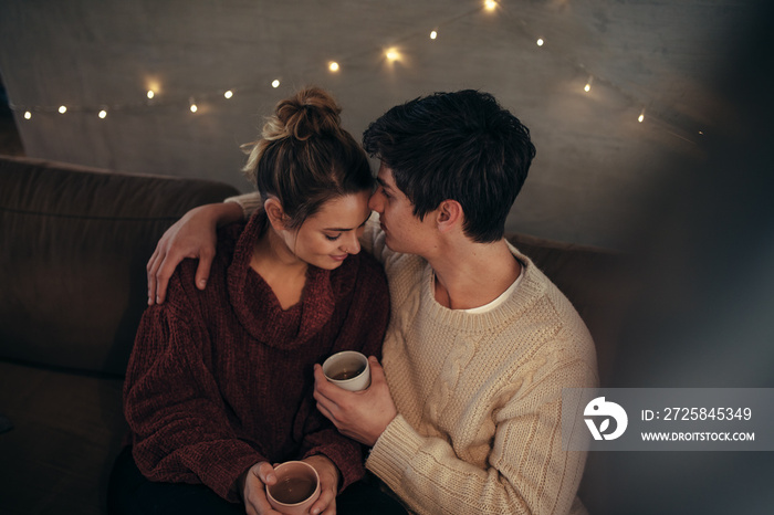 Cozy couple sitting together on sofa with coffee