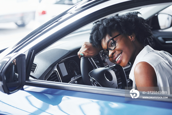 开心一笑。年轻的非裔美国妇女坐在现代新车里