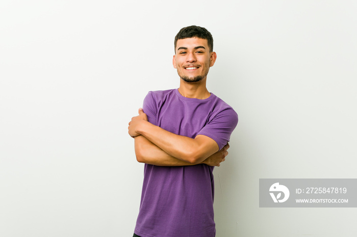 Young hispanic man hugs, smiling carefree and happy.