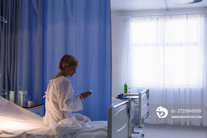 Female patient using smart phone in hospital bed