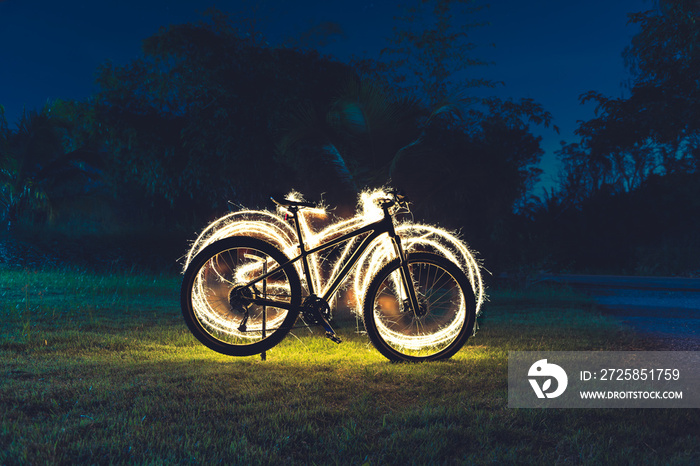 绿色草地上的山地自行车剪影，夜晚美丽的烟花闪烁的心脏象征