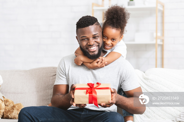 Loving little daughter giving gift to her dad