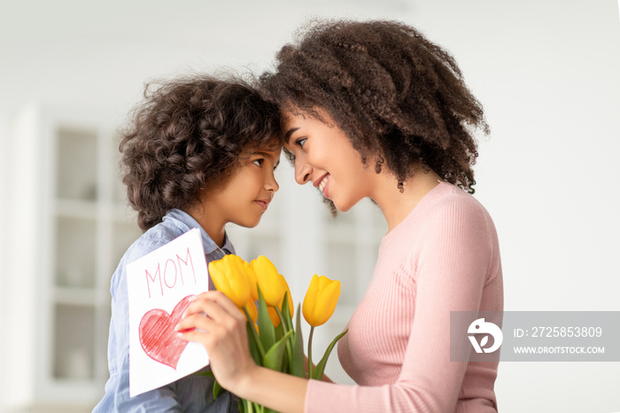Black girl greeting mom with tulips and card
