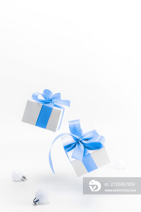 Holiday winter blue. White gift box with blue ribbon, New Year balls in Christmas composition on whi