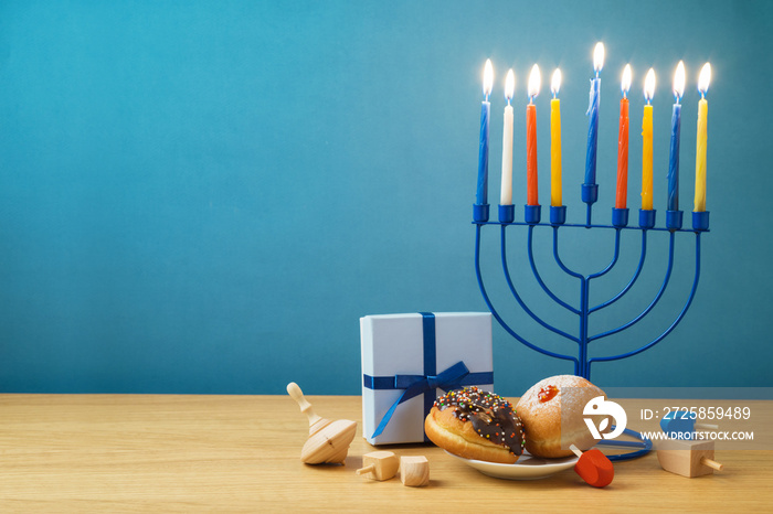 Jewish holiday Hanukkah background with menorah, sufganiyot, gift box and spinning top on wooden tab